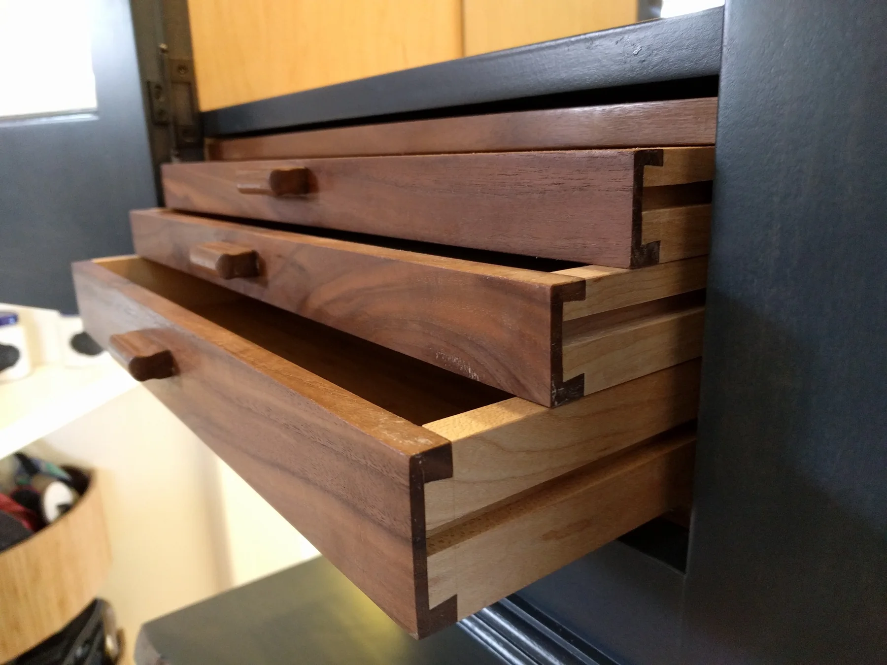 Solid wood dovetailed drawers extended from a dark-finished cabinet