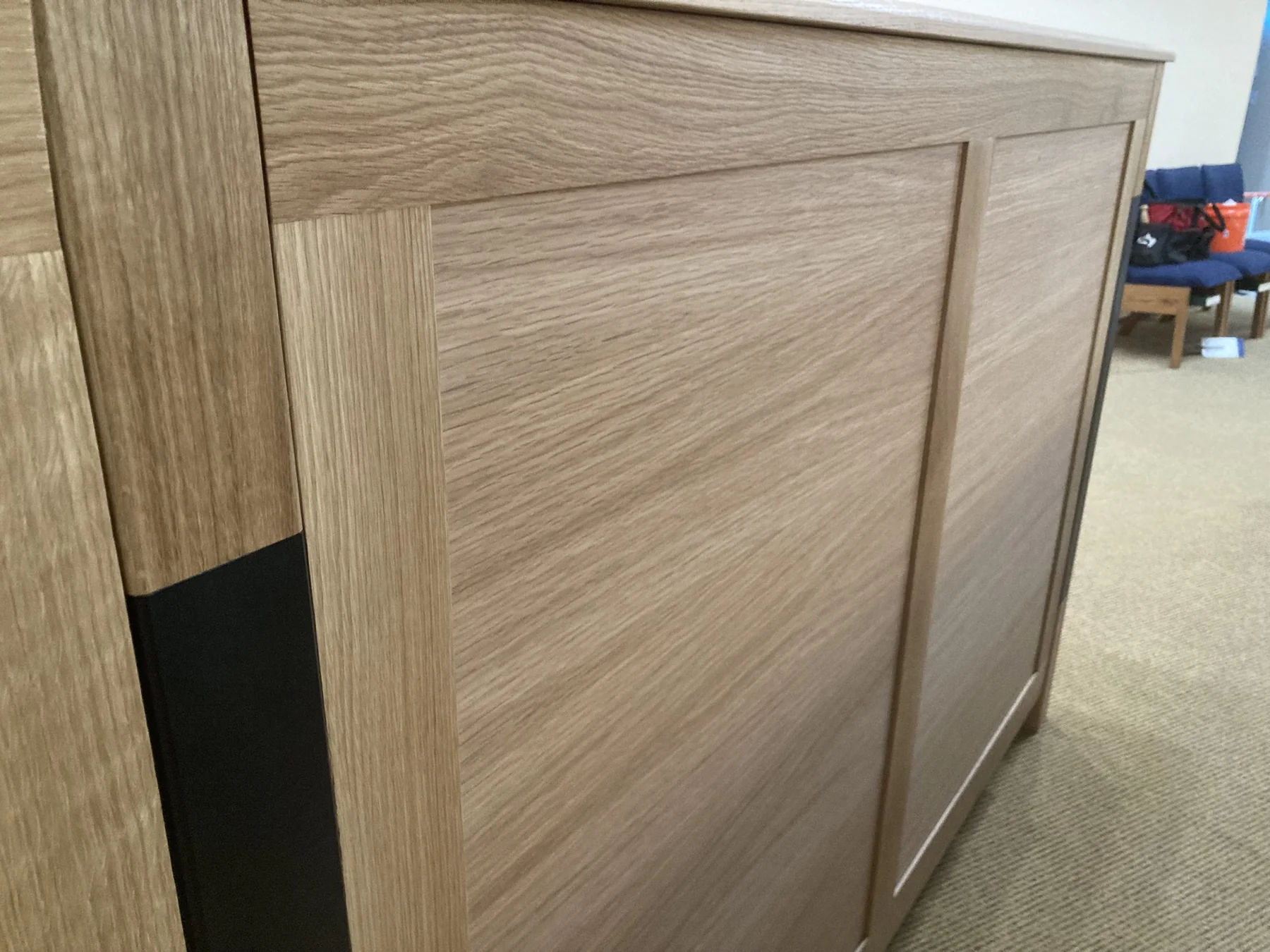Close view of framed White Oak panels meeting a dark vertical inlay
